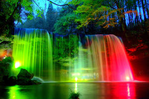 Spectacular Rainbow Seen Through The Cascading Waters Of A Majestic Waterfall Wallpaper