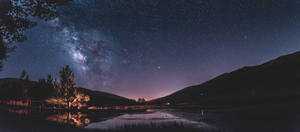 Sprawling Lake With Blue And Purple Galaxy Wallpaper