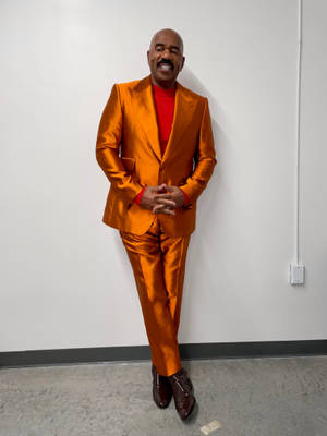 Steve Harvey Wearing An Orange Suit Wallpaper