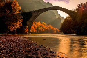 Stone Bridge Connected To The Riverside Wallpaper