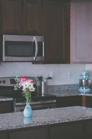 Stylish Kitchen Design With An Aesthetic Flower Vase On A Grey Marble Countertop Wallpaper