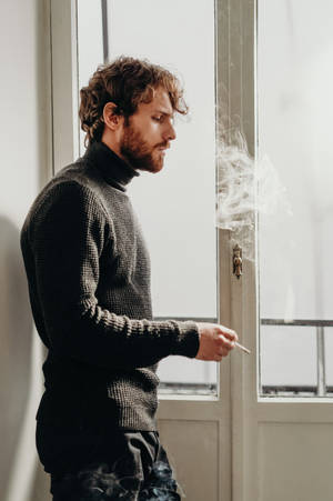 Stylishly Rugged Man Enjoying A Cigar Wallpaper