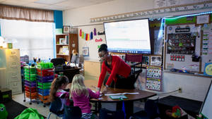 Teacher Helping Students Answer Test Paper Wallpaper