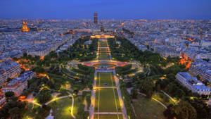 The Eiffel Tower Lights Up The Champ De Mars In Paris At Dusk Wallpaper
