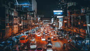 The Glittering Lights Of A Busy City Street At Night Wallpaper