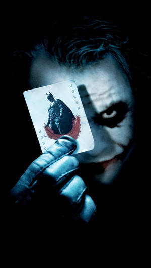 The Joker Holding A Playing Card Wallpaper