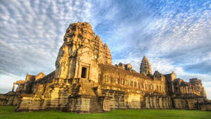 The Majestic Angkor Wat Amidst Verdant Greenery Under A Clear Blue Sky Wallpaper
