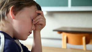 The Overwhelming Side Of Stress: A Distressed And Anxious Child Holding Head In Hands. Wallpaper