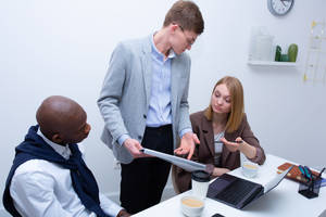 Three Co-workers Engaging In A Business Discussion Wallpaper