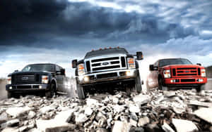 Three Lifted Trucks On Rocky Terrain Wallpaper