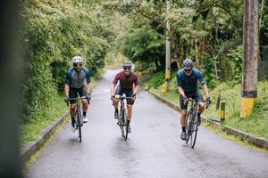 Three Men Cycling Country Road Wallpaper