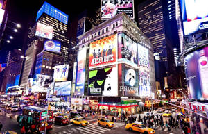 Times Square At Night With Many People And Cars Wallpaper