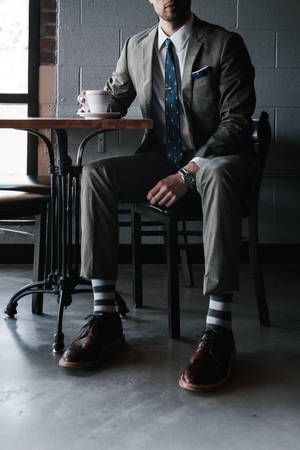 Trendy Man In Stylish Attire Posing At A Café Wallpaper