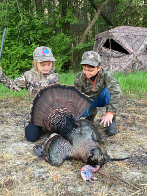 Two Children Posing With A Turkey Wallpaper