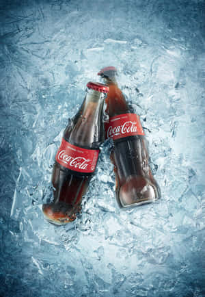 Two Coca Cola Bottles On Ice Wallpaper