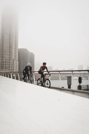 Two Cycling Women City Bridge Wallpaper