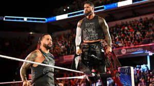 Two Wrestlers Standing On The Ring In Front Of A Crowd Wallpaper