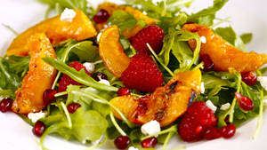 Vibrant Arugula Salad With Berries, Peaches And Pomegranate Wallpaper