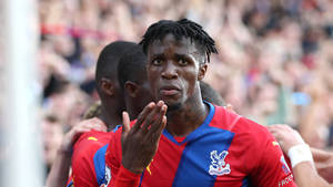 Wilfried Zaha With Teammates Behind Him Wallpaper