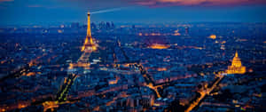 ​witness The Beauty Of The Paris Skyline At Night Wallpaper