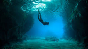 Woman Diving In Between Natural Underwater Structures Wallpaper
