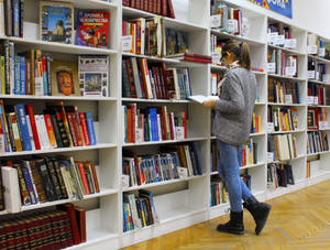 Woman Reading Reference Book Near Shelf Wallpaper