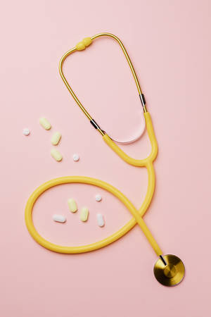Yellow Stethoscope On Pink Background Wallpaper