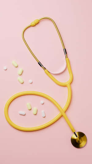 Yellow Stethoscopeand Pillson Pink Background Wallpaper