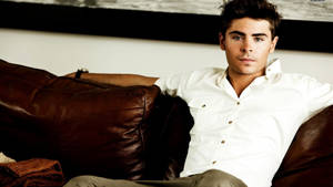 Zac Efron In Brown Couch Wallpaper